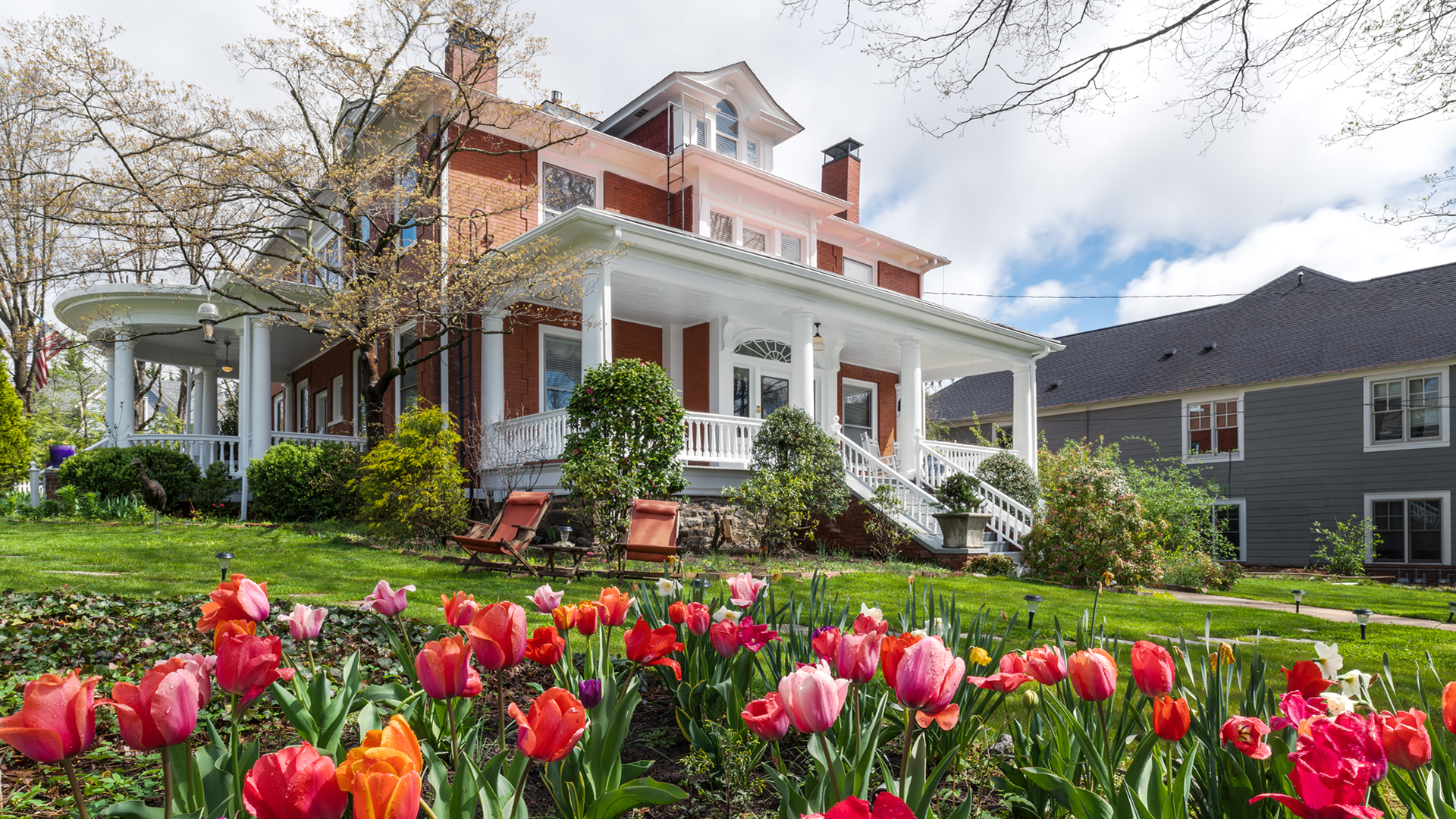 Chestnut Street Inn Red Brick Exterior Two Story with Dormer, White Front and Side Porch with Tulips in foreground