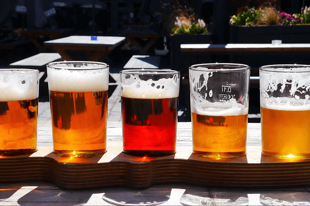 Multiple Glasses of beer lined up on bar outside