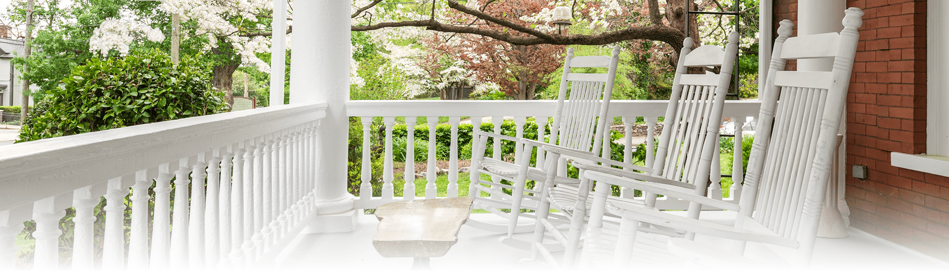 Three white patio rocking chairs place on the porch